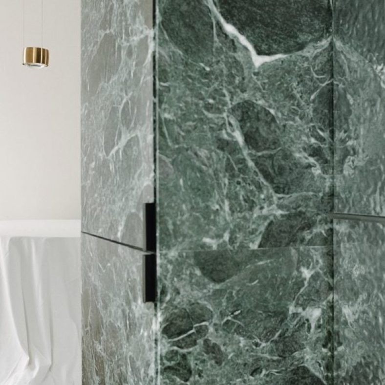 Monolithic green marble carves apartment interior in Milan by AIM Studio